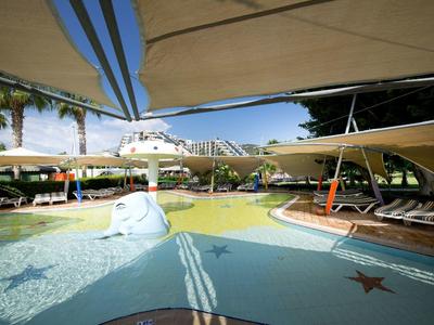 Outdoor pool area with shaded lounge chairs and playful water features under large canopies.