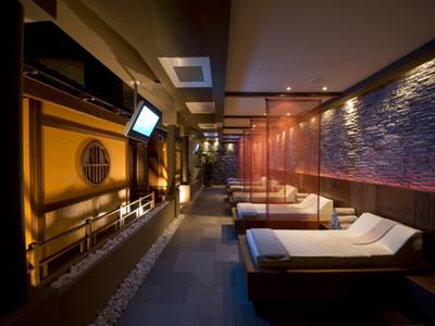 Dimly lit spa corridor with lounge chairs and water feature on the left side.