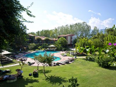 Jardin d'hôtel avec piscine, chaises longues et verdure luxuriante sous un ciel bleu