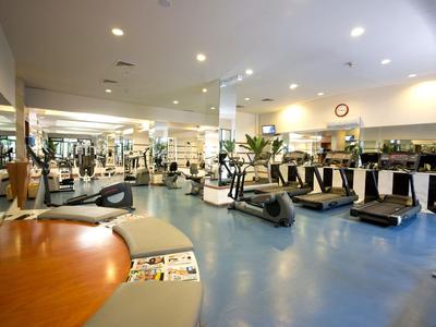 Grande salle de sport avec tapis de course, équipements de fitness et miroirs muraux.