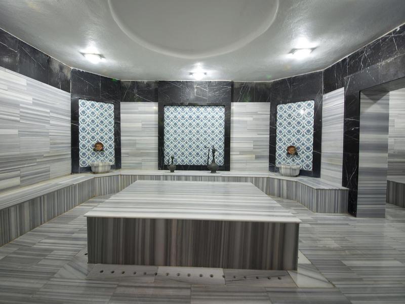 Spacious marble Turkish bath with large central platform and wall niches with faucets.