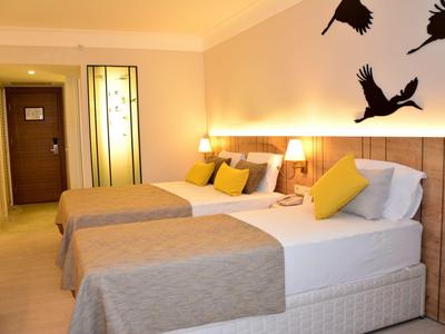 Camera d'hotel con due letti, colori neutri e decorazione murale con uccelli