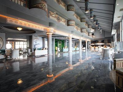 Großer, heller Innenraum mit Säulen, Marmorfußboden und Sitzbereichen in modernem Stil.