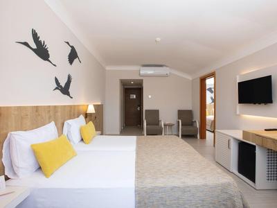 Camera d'albergo moderna con due letti, cuscini gialli, decorazioni murali e TV a schermo piatto.