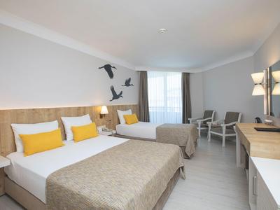 Modern eingerichtetes Hotelzimmer mit zwei großen Betten, Sitzbereich und Schreibtisch.