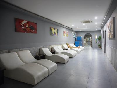 Sala relax moderna con poltrone bianche, opere d'arte colorate e pareti grigie.