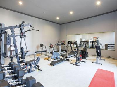 Moderner Fitnessraum mit verschiedenen Trainingsgeräten und Hanteln in einem hellen Raum.