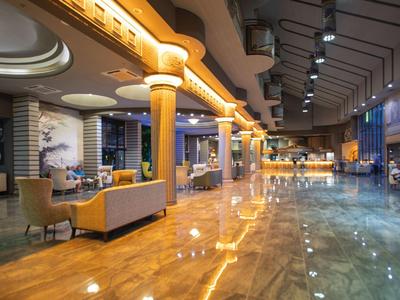 Lobby dell'hotel elegante con pavimento lucido, illuminazione moderna e aree salotto.