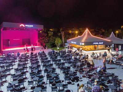 Freiluftkino mit vielen Stühlen und beleuchtetem Verkaufsstand bei Nacht.