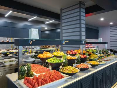 Buffet di frutta colorata con meloni, ananas e uva in un ristorante moderno.