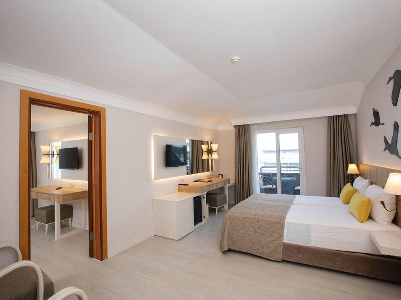 Camera d'hotel moderna con letto matrimoniale, scrivania e balcone con vista mare.