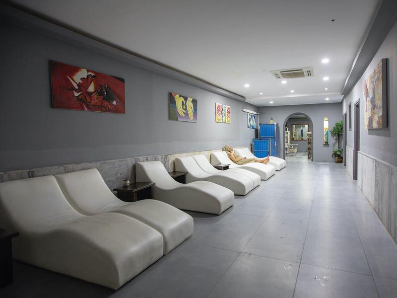 Sala relax moderna con poltrone bianche, opere d'arte colorate e pareti grigie.