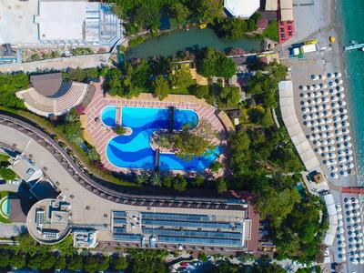 Vista aerea di un resort con piscina, spiaggia e lettini vicino al mare.