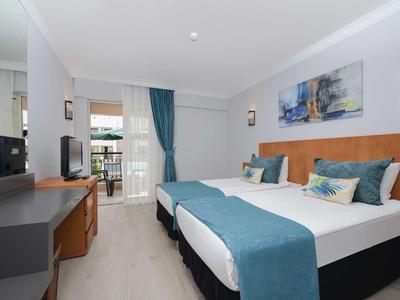 Nowoczesny pokój hotelowy z podwójnym łóżkiem, biurkiem i balkonem z widokiem na zewnątrz.