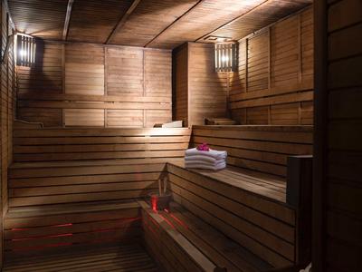Sauna accogliente con panche di legno, luce calda e asciugamani freschi.