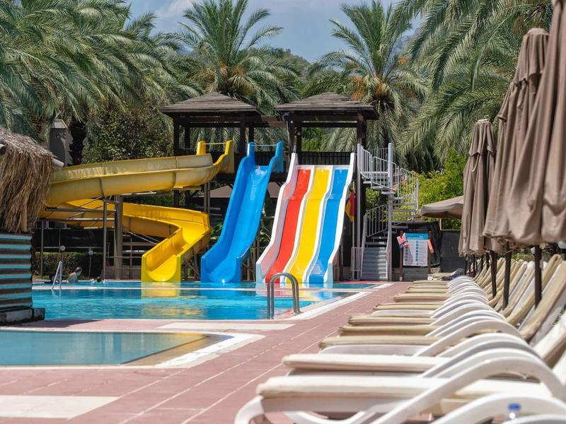 Parco acquatico con scivoli colorati e lettini in una giornata di sole.