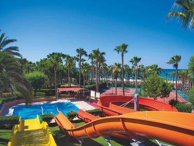 Bunte Wasserrutschen und Pools in einem tropischen Wasserpark mit Palmen unter blauem Himmel.