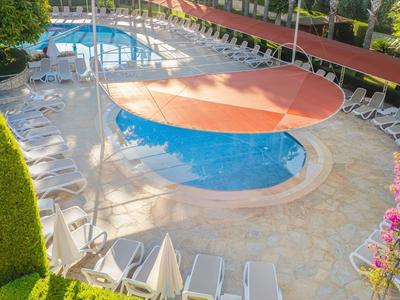 Moderner Poolbereich mit rundem Becken, orangefarbenem Sonnenschutz und weißen Liegestühlen.