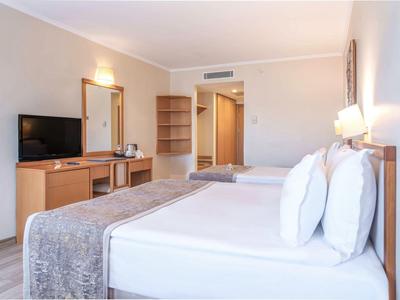 Modern eingerichtetes Hotelzimmer mit Doppelbett, Schreibtisch, Fernseher und warmem Licht.