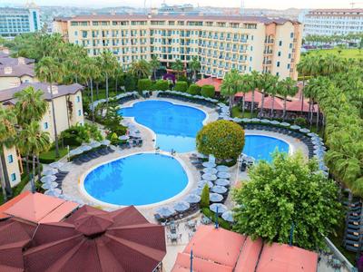 Grande piscina dell'hotel con forme rotonde e ovali, circondata da lettini e palme.
