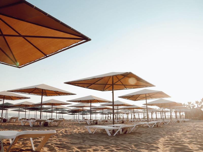 Spiaggia vuota con numerosi lettini e ombrelloni all'alba o al tramonto.