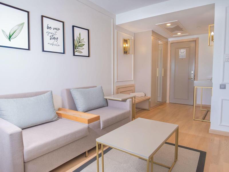 Luminoso area d'attesa dell'hotel con due divani grigi, opere d'arte moderne e tavolino.