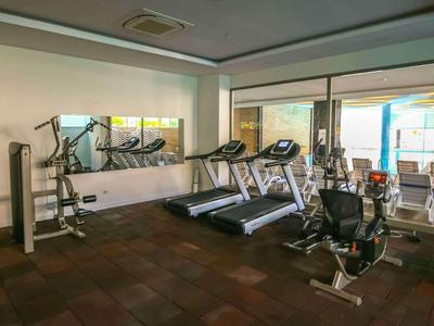 Světelná posilovna s různými cvičebními stroji a velkými okny.