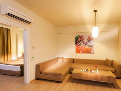 Area soggiorno moderna in hotel con divani marroni, tavolino in legno e quadro alle pareti.