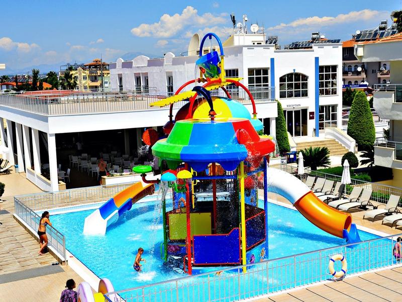 Area giochi acquatica colorata con scivoli in piscina dell'hotel sotto il cielo blu.
