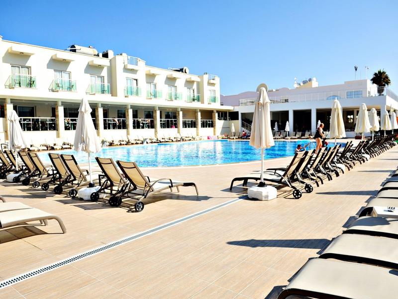 Area piscina moderna dell'hotel con lettini e ombrelloni sotto un cielo limpido.
