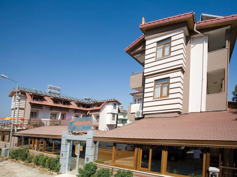 Mehrstöckiges Hotelgebäude mit braunem Dach unter blauem Himmel.
