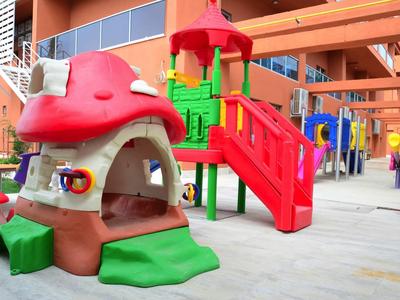 Bunte Kinderspielgeräte aus Kunststoff mit Rutsche und Pilzhaus auf einem Hof vor Wohngebäude.