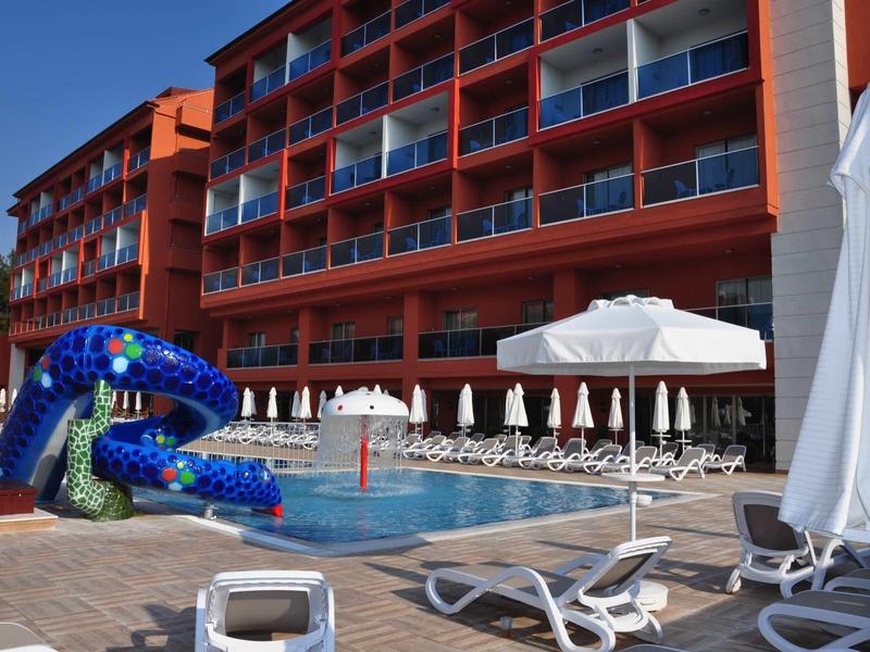 Un hotel con piscina all'aperto, lettini e ombrelloni in una giornata di sole.
