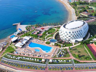 Luftaufnahme von Hotel mit großem Pool, Strand und blauer Meeresküste im sonnigen Küstengebiet.