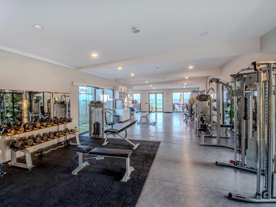 Grote sportschool met verschillende fitnessapparaten en dumbbells in een modern hotel.