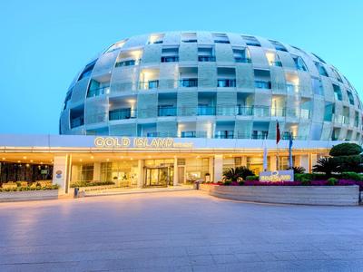 Bâtiment d'hôtel ovale moderne avec façade en verre et chambres éclairées au crépuscule.