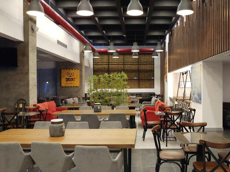 Intérieur moderne d'un café avec tables, chaises et décoration végétale.