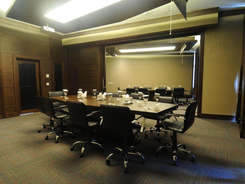 Salle de réunion moderne avec grandes tables et chaises noires confortables.