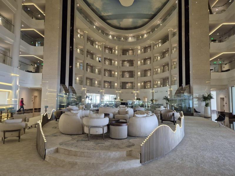 Hall d'hôtel spacieux avec fauteuils ronds et balustrades dorées élégantes.