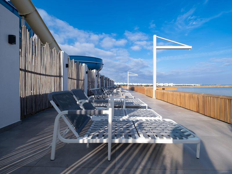 Chaises longues vides près de la piscine avec ciel bleu et rambarde en bois