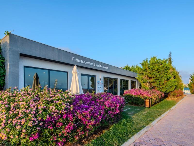 Centre de fitness moderne avec jardin fleuri et allée sous un ciel clair