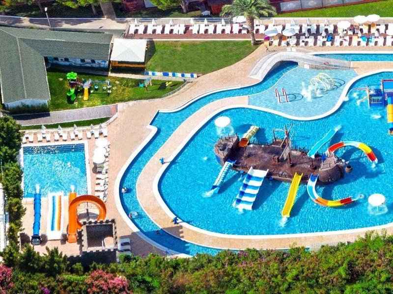 Vista aérea de un parque acuático con varias piscinas y toboganes en un complejo vacacional.