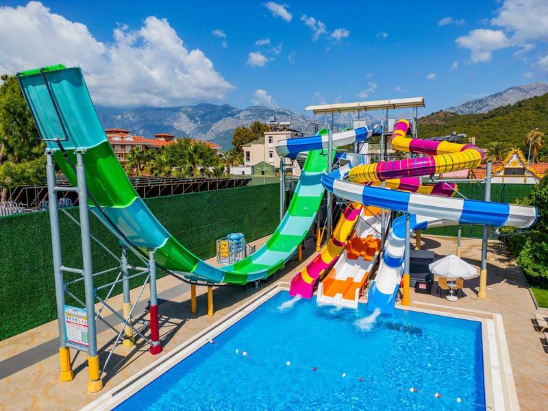Parque acuático al aire libre con varios toboganes de agua coloridos sobre una piscina