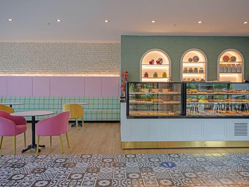 Lounge moderna de hotel con sillas coloridas, mostrador y suelo decorativo.