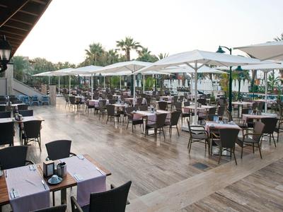 Große Außenrestaurant-Terrasse mit Tischen, Stühlen und Sonnenschirmen bei Tageslicht.