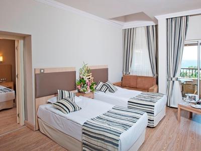 Modernes Hotelzimmer mit zwei Einzelbetten, Holzboden, großer Fensterfront und Blick ins Grüne.