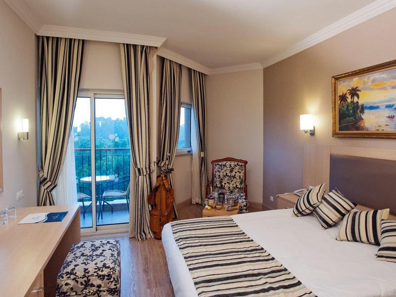 Bright hotel room with double bed, balcony, and sea view.