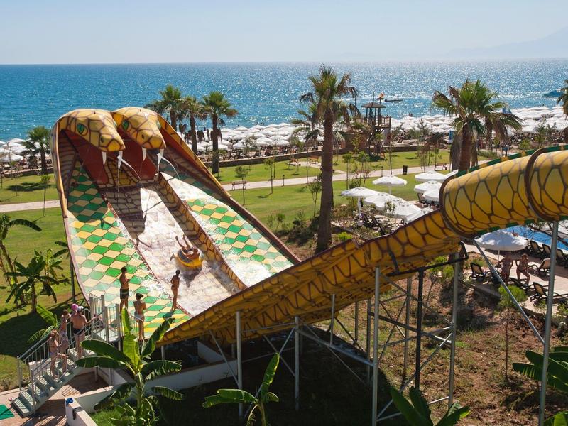Water slide with snake design in tropical hotel garden by the sea