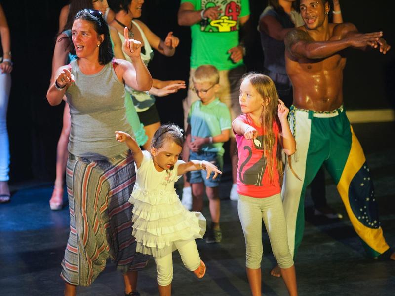 People happily dancing in colorful clothes on a dance floor.