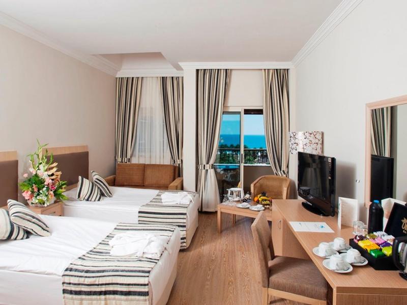 Modern hotel room with two beds, balcony, and sea view.